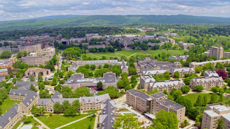 鸟瞰图, gray Hokie Stone buildings are tucked between greenery in a mountain valley on a clear, 阳光灿烂的日子.